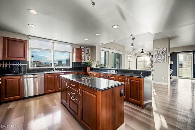 kitchen featuring a sink, light wood-style floors, dishwasher, a center island, and a peninsula