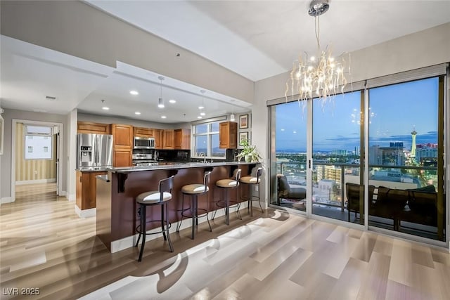 150 Las Vegas Blvd Unit 1507, Las Vegas, NV 89101 - kitchen with a kitchen bar, appliances with stainless steel finishes, brown cabinets, a notable chandelier, and light wood-style flooring