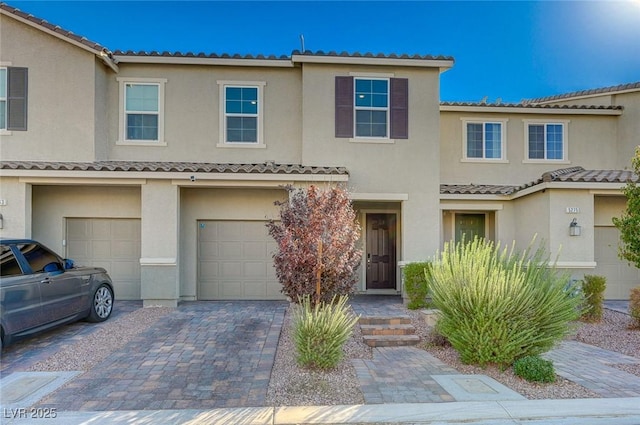view of property with a garage, stucco siding, driveway, and a tile roof