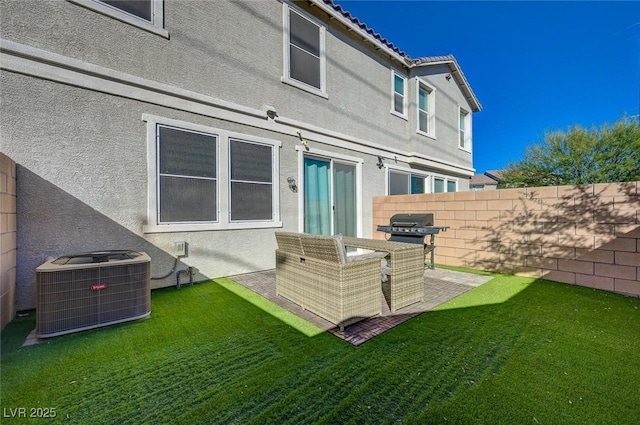 back of house featuring stucco siding, central air condition unit, a yard, and fence