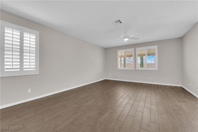 unfurnished room with baseboards, ceiling fan, dark wood finished floors, and visible vents