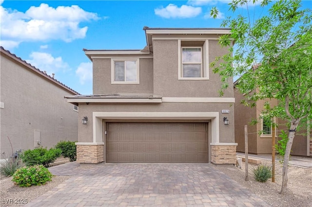 view of front facade with an attached garage, decorative driveway, stucco siding, and stone siding