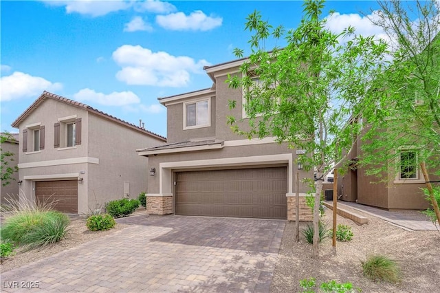 view of front of home featuring decorative driveway, a garage, stone siding, and stucco siding