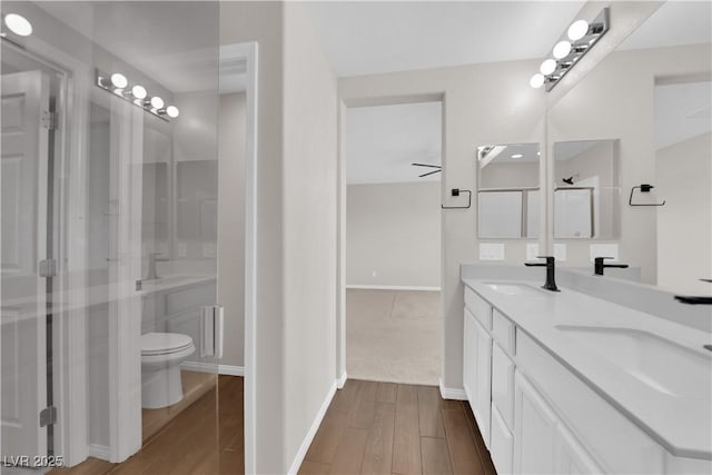 bathroom featuring a sink, baseboards, double vanity, and wood finished floors