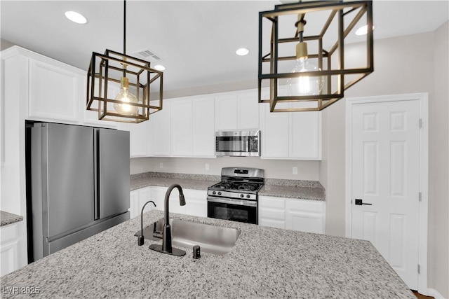 kitchen featuring an inviting chandelier, light stone countertops, white cabinetry, a sink, and appliances with stainless steel finishes