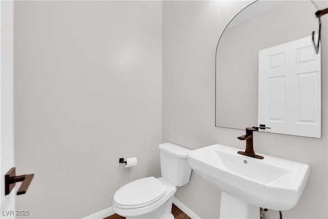 bathroom featuring toilet, baseboards, and a sink
