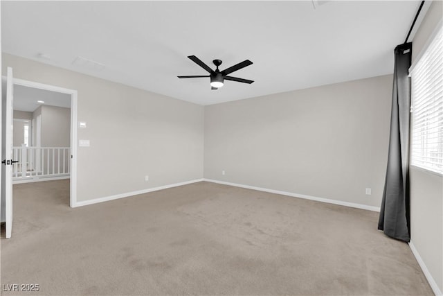 empty room with baseboards, a ceiling fan, and light colored carpet