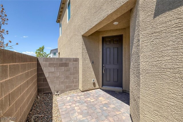 doorway to property with fence and stucco siding