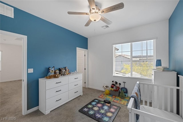 carpeted bedroom featuring a crib, baseboards, a ceiling fan, and visible vents