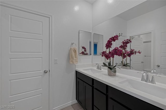 bathroom featuring double vanity, a sink, baseboards, and tile patterned flooring