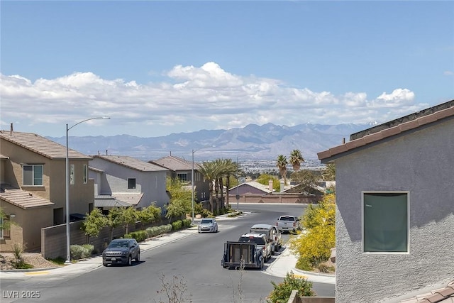 view of street with a residential view, a mountain view, street lighting, and curbs