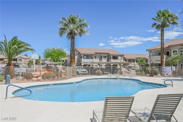 community pool with fence, a patio, and a residential view
