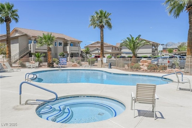 community pool with a patio, a community hot tub, fence, and a residential view