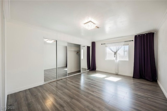 unfurnished bedroom with a closet, baseboards, crown molding, and wood finished floors