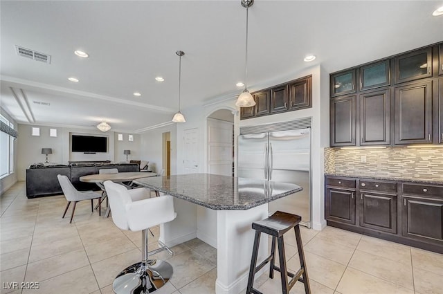 kitchen featuring visible vents, built in fridge, light tile patterned floors, and a kitchen bar