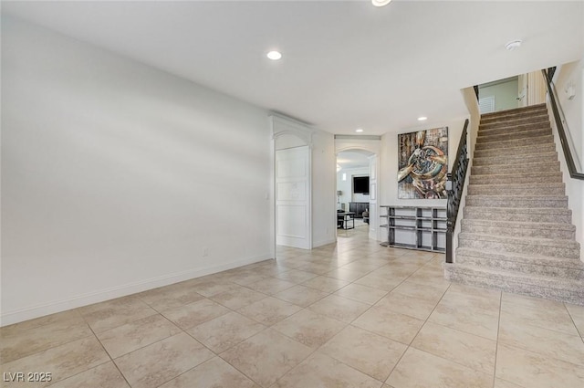 interior space featuring light tile patterned flooring, arched walkways, stairs, recessed lighting, and baseboards