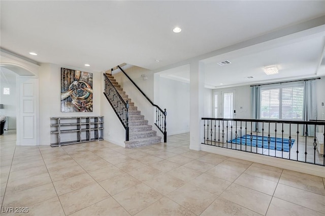 tiled empty room with recessed lighting, arched walkways, stairs, and visible vents