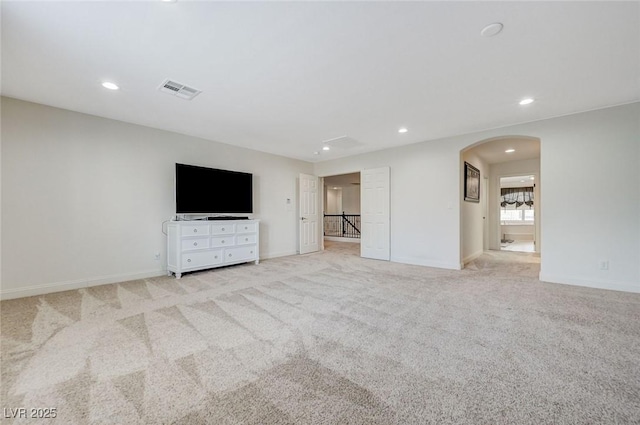unfurnished living room featuring visible vents, arched walkways, baseboards, light carpet, and recessed lighting