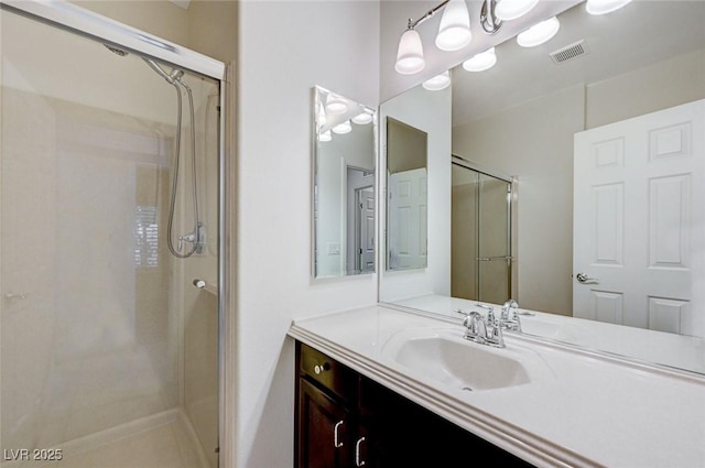 full bath with visible vents, vanity, and a shower stall