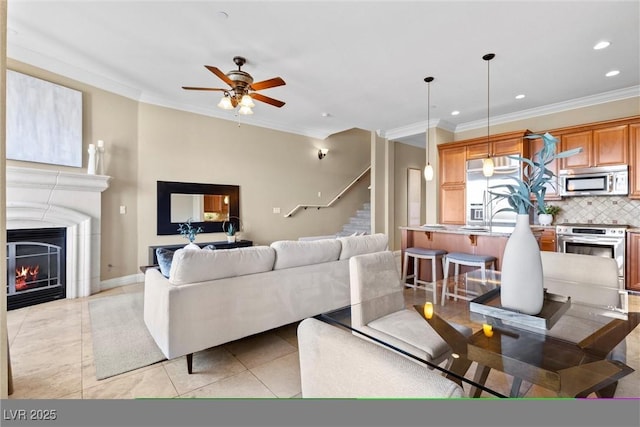 living area with recessed lighting, ceiling fan, ornamental molding, and stairway