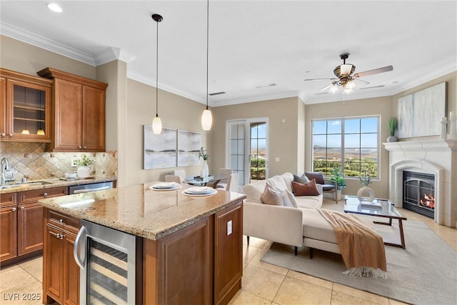 20 Via Visione Unit 105, Henderson, NV 89011 - kitchen with brown cabinets, a sink, light stone counters, beverage cooler, and open floor plan
