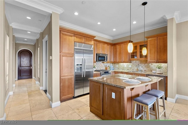 kitchen featuring brown cabinets, a sink, arched walkways, stainless steel appliances, and tasteful backsplash