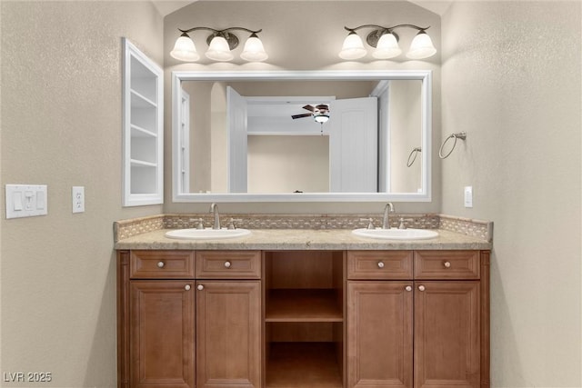full bathroom featuring double vanity, a textured wall, and a sink
