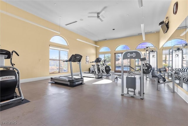 gym featuring a ceiling fan, baseboards, and plenty of natural light
