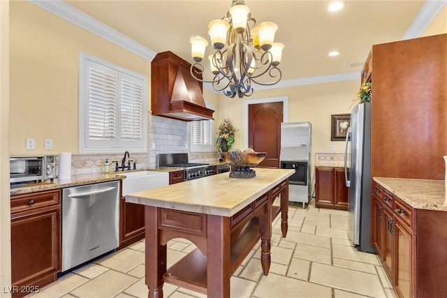 kitchen featuring an inviting chandelier, ornamental molding, custom exhaust hood, and stainless steel appliances
