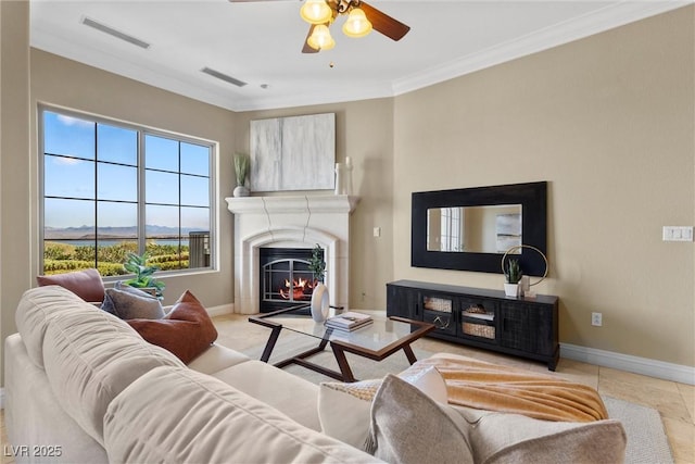 living room featuring baseboards, a ceiling fan, a warm lit fireplace, and visible vents