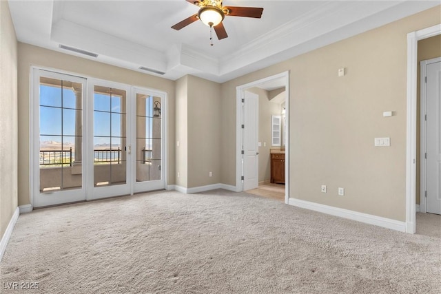 unfurnished room featuring carpet floors, a ceiling fan, baseboards, a tray ceiling, and visible vents