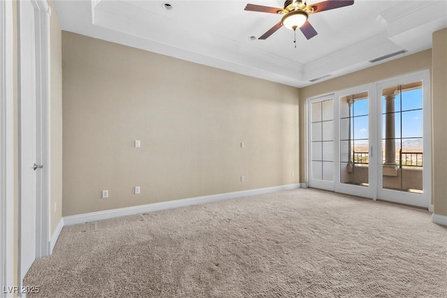 carpeted empty room featuring visible vents, ornamental molding, baseboards, ceiling fan, and a tray ceiling