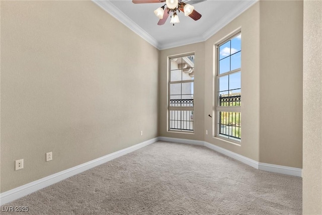 carpeted spare room featuring baseboards, ornamental molding, a ceiling fan, and a wealth of natural light