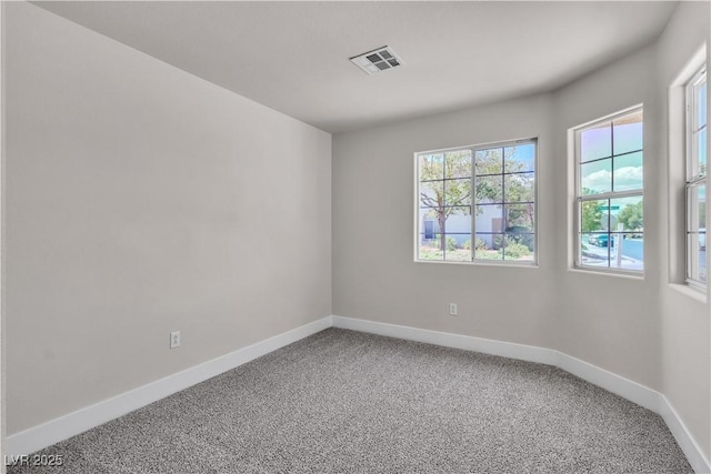 empty room with carpet floors, baseboards, and visible vents
