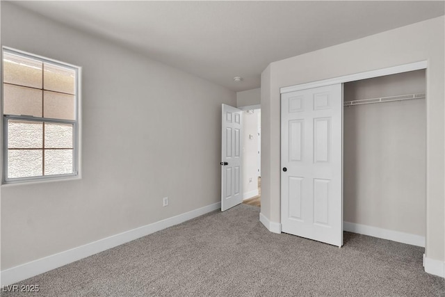 unfurnished bedroom with a closet, carpet, baseboards, and multiple windows