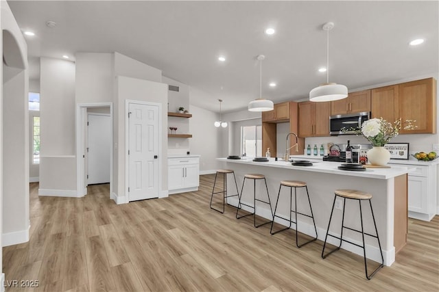 kitchen with a kitchen breakfast bar, open shelves, stainless steel microwave, light wood-style floors, and recessed lighting