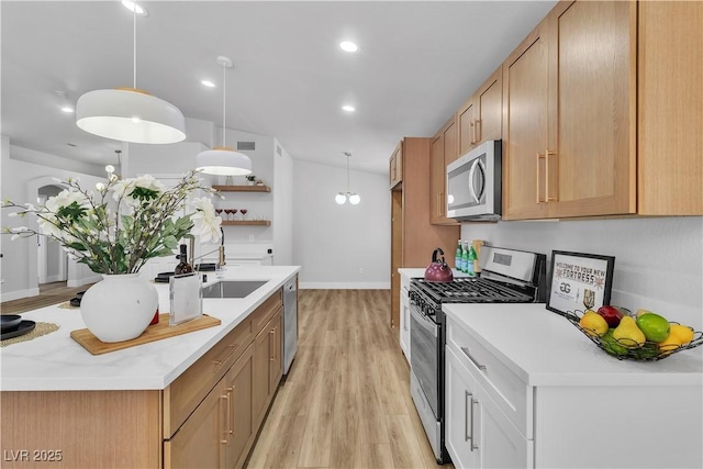 kitchen featuring a sink, light countertops, stainless steel appliances, decorative light fixtures, and light wood-type flooring