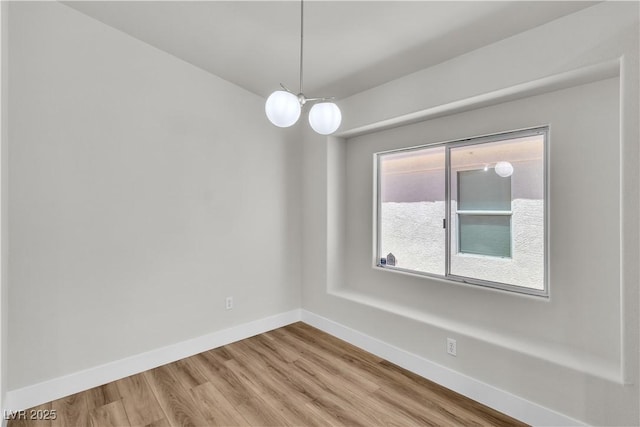 spare room with baseboards and light wood-style flooring