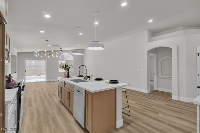 kitchen with dishwashing machine, light wood-type flooring, arched walkways, range with gas cooktop, and a sink