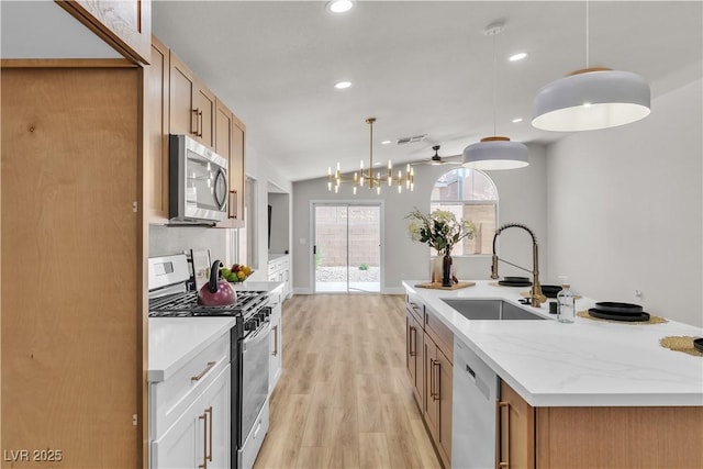 kitchen with a kitchen island with sink, light wood-type flooring, a sink, lofted ceiling, and stainless steel appliances