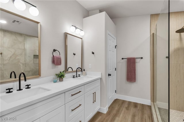 bathroom with a walk in shower, visible vents, a sink, and wood finished floors