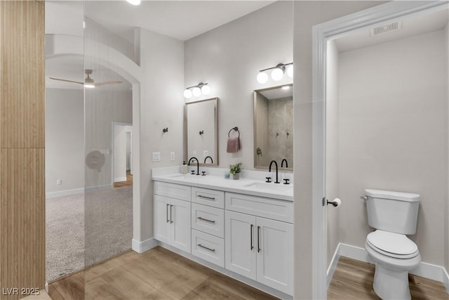 bathroom featuring double vanity, visible vents, a sink, and wood finished floors