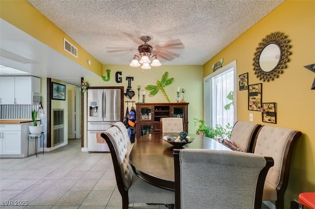 dining space with ceiling fan, light tile patterned flooring, a textured ceiling, and visible vents