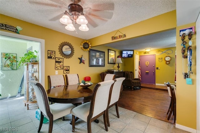 dining area with baseboards, a ceiling fan, a textured ceiling, and light tile patterned flooring