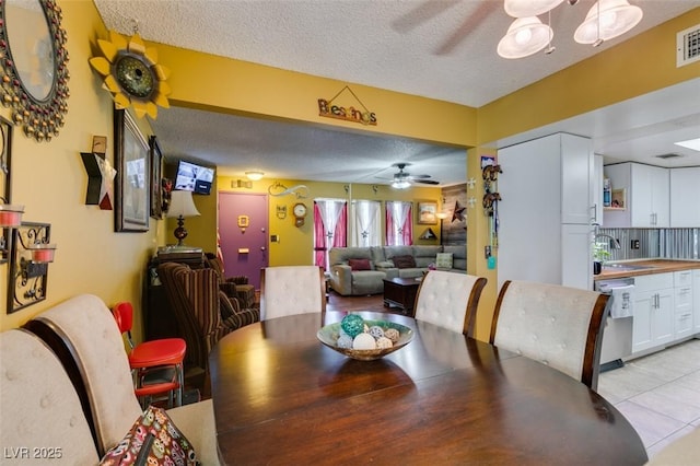 dining area featuring visible vents, a textured ceiling, ceiling fan, and light tile patterned flooring