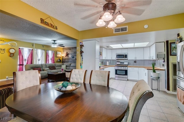 dining space featuring a textured ceiling, ceiling fan, visible vents, and light tile patterned flooring