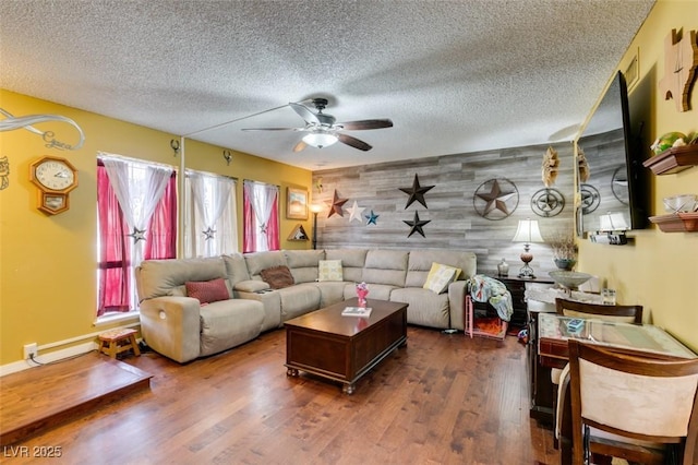 living area featuring ceiling fan, a textured ceiling, wood walls, an accent wall, and wood finished floors