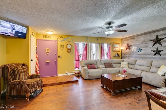 living room with ceiling fan, a textured ceiling, an accent wall, and wood finished floors