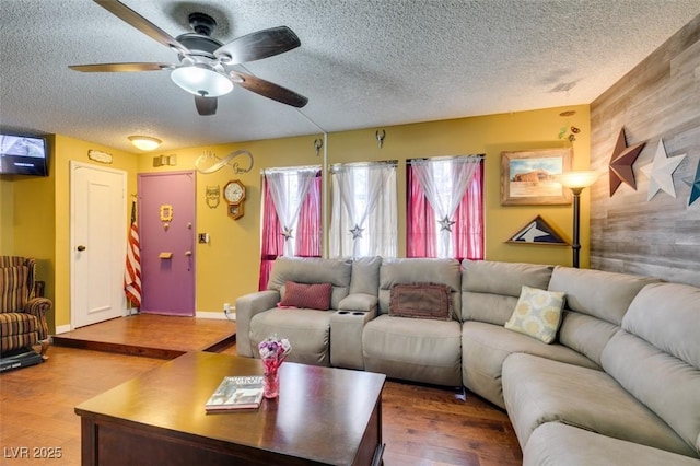 living room with baseboards, a textured ceiling, ceiling fan, and wood finished floors