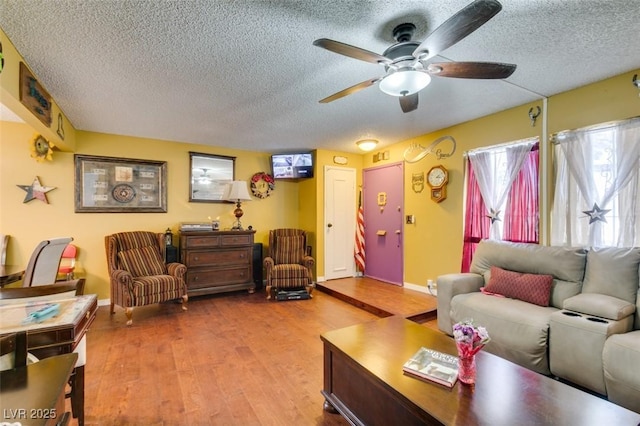 living area with baseboards, ceiling fan, a textured ceiling, and wood finished floors